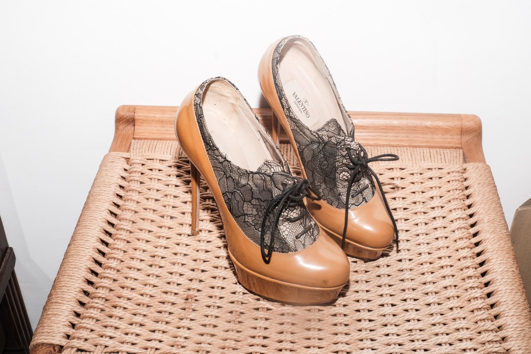 Tan leather platform heels with black lace detailing on a woven wicker chair.