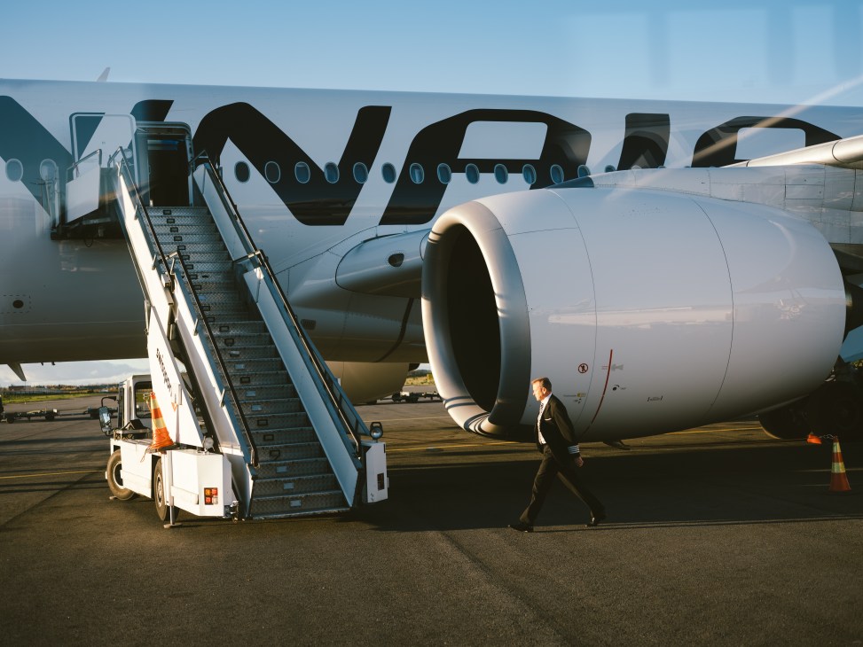 A businessman walks past a Finnair aircraft with its distinctive livery on the tarmac at an airport.