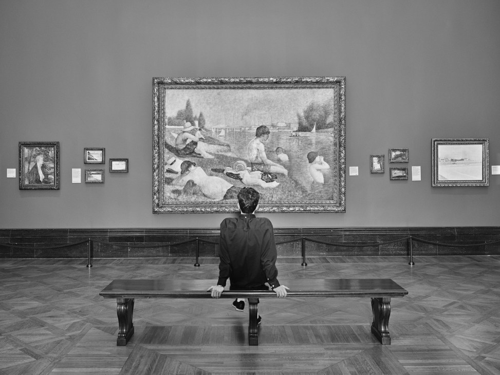 Person sitting alone on museum bench viewing large classical painting of figures by water