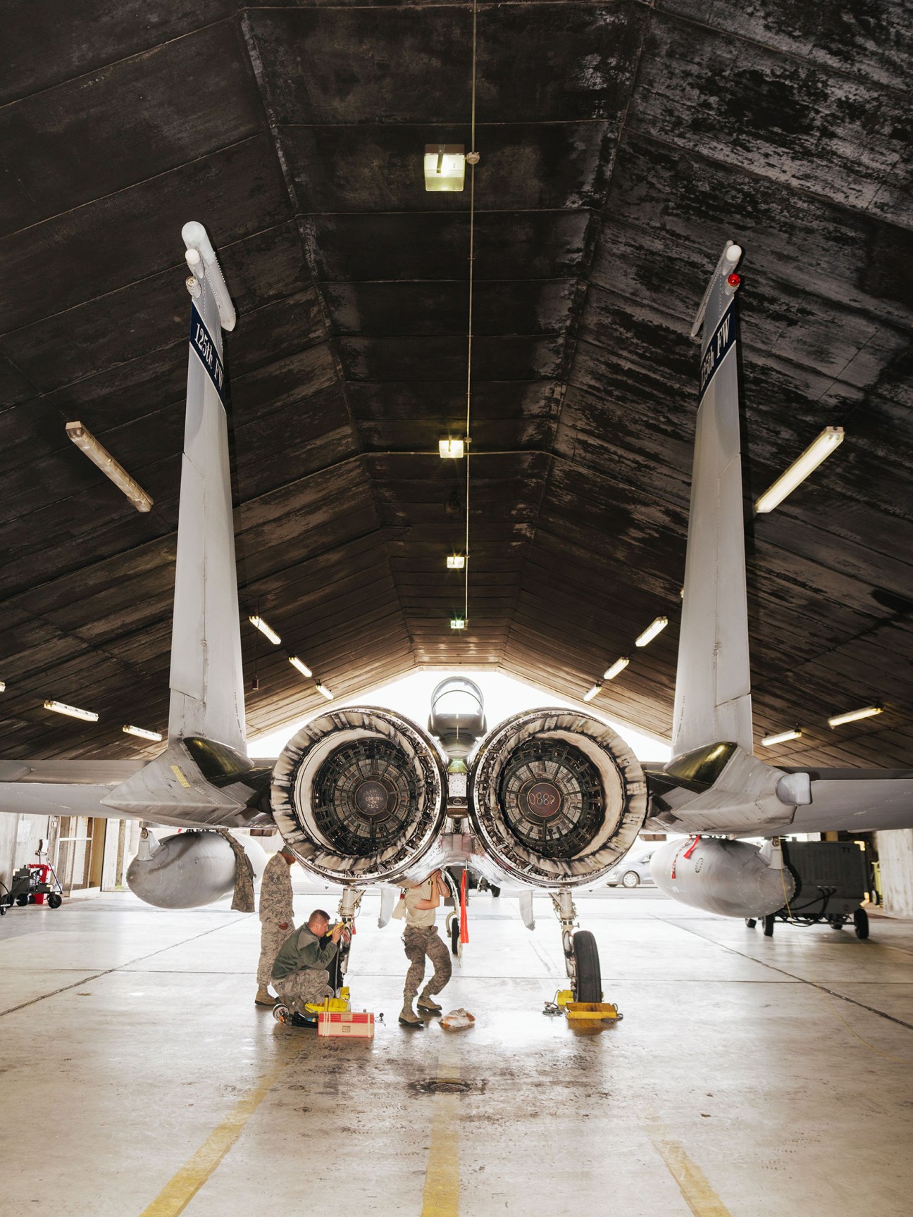 Maintenance crew members work on an F-15C Eagle fighter jet inside a hangar at Keflavík air base.