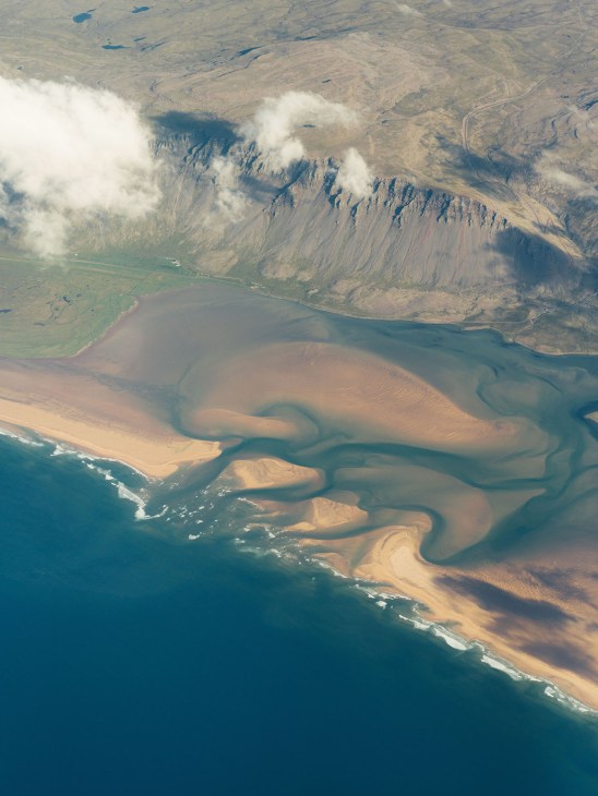 Aerial view of Iceland's Reykjanes peninsula showing snow-capped mountains, coastal waters, and volcanic terrain.