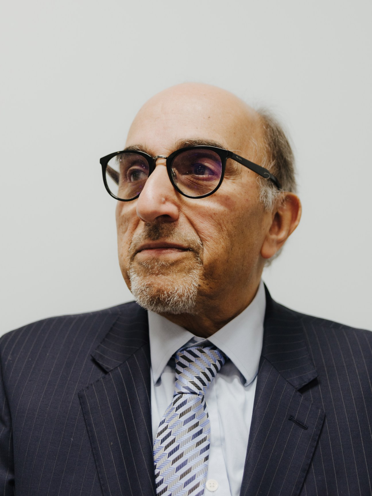 Portrait of Hafiz Elkabbany, Egyptian journalist at Asharq Alawsat, wearing glasses and pinstriped suit.