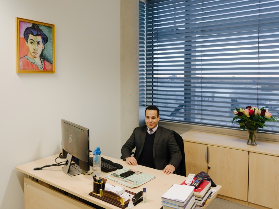 Adhwan Alahmari, head of digital media, sits at his desk in a modern office with a colorful portrait on the wall.