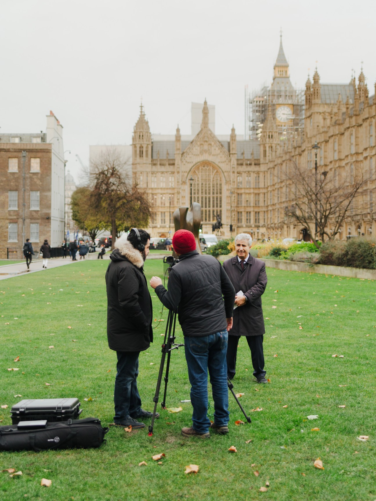 Film crew interviewing a man in front of the Houses of Parliament in London.