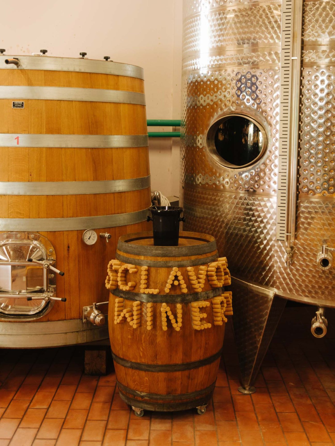 Wooden wine barrels and stainless steel tanks at Sclavos winery with a barrel decorated with cork corks spelling 'ALAWI WINERY'.