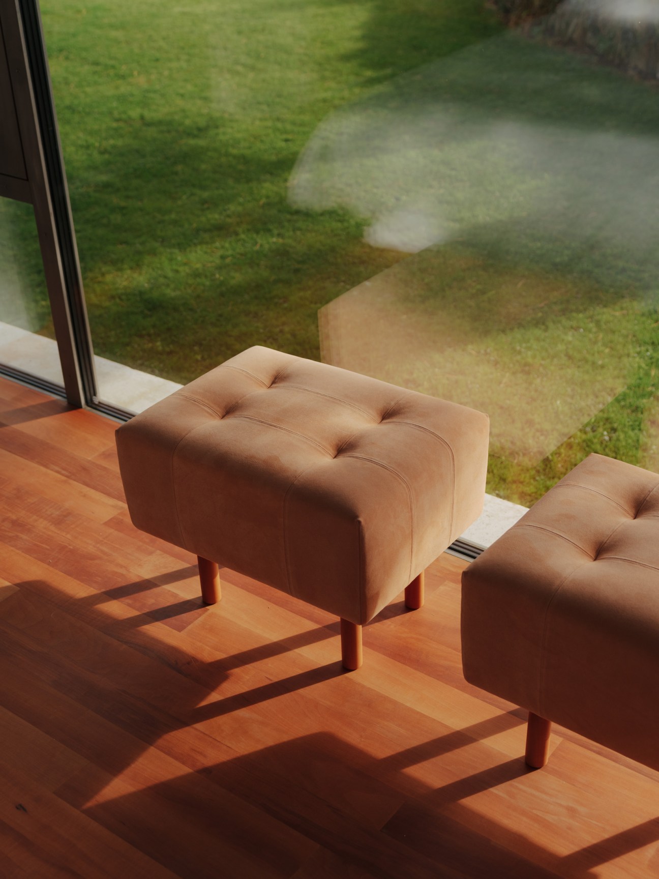 Tan leather ottoman by a window overlooking Devon countryside fields.