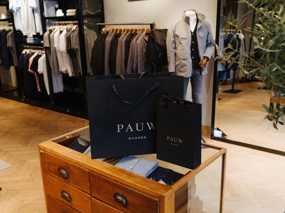 Pauw Mannen navy shopping bags with gold lettering displayed in a menswear shop.