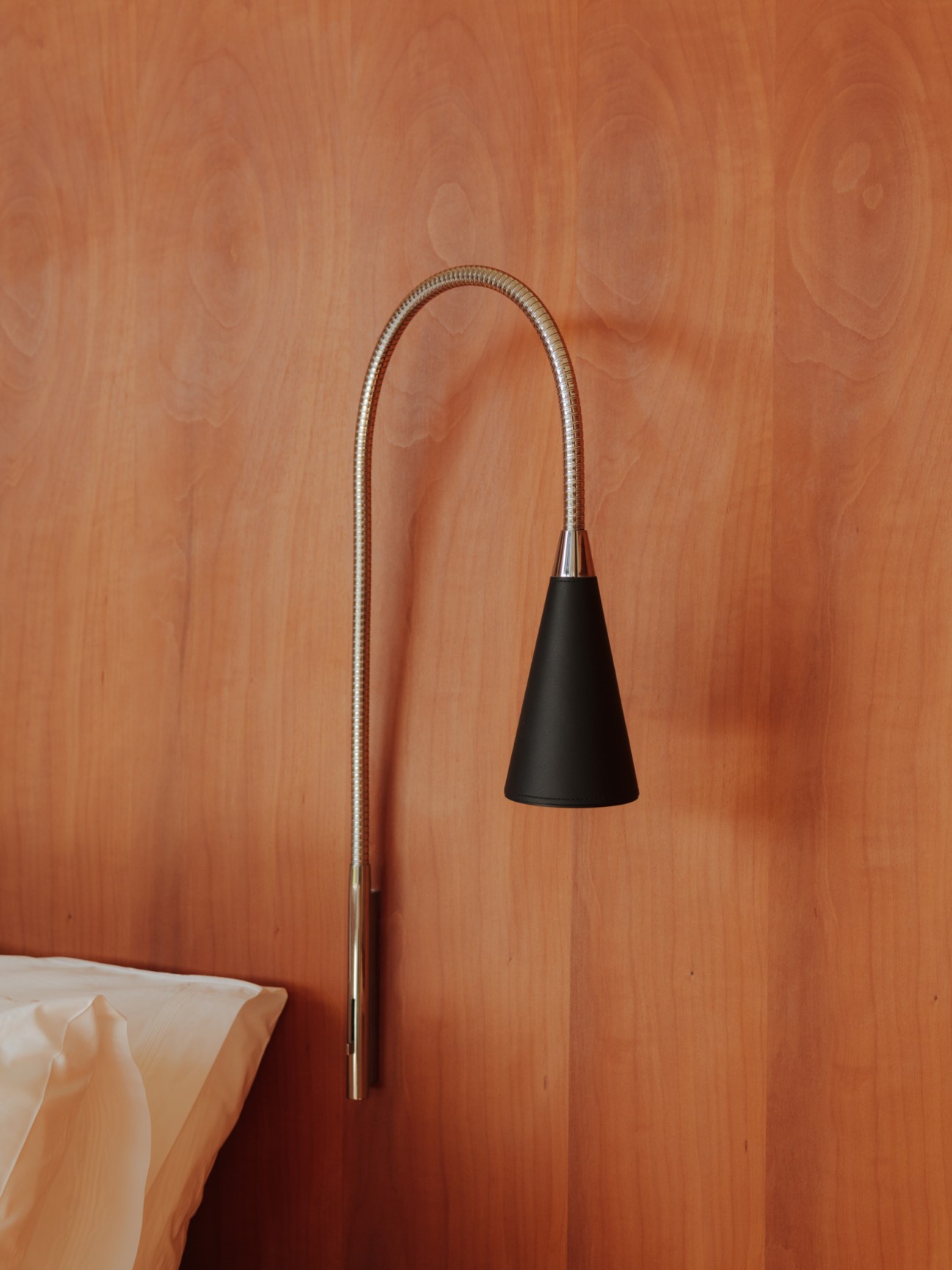 A minimalist reading light with a curved metal arm and black conical shade mounted on a warm wood wall.