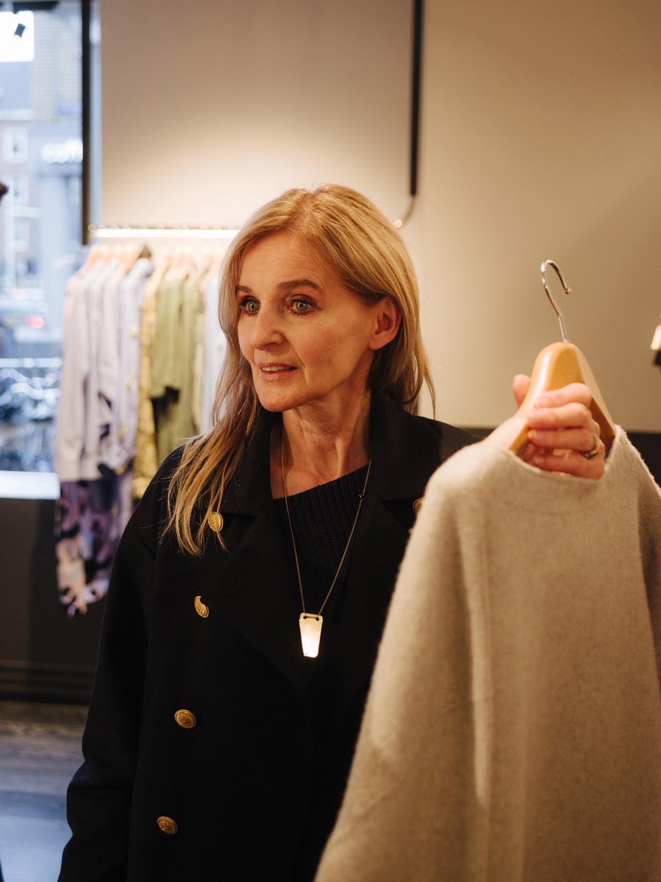 Madeleine Pauw holds up a beige cashmere garment on a hanger in her Amsterdam shop.