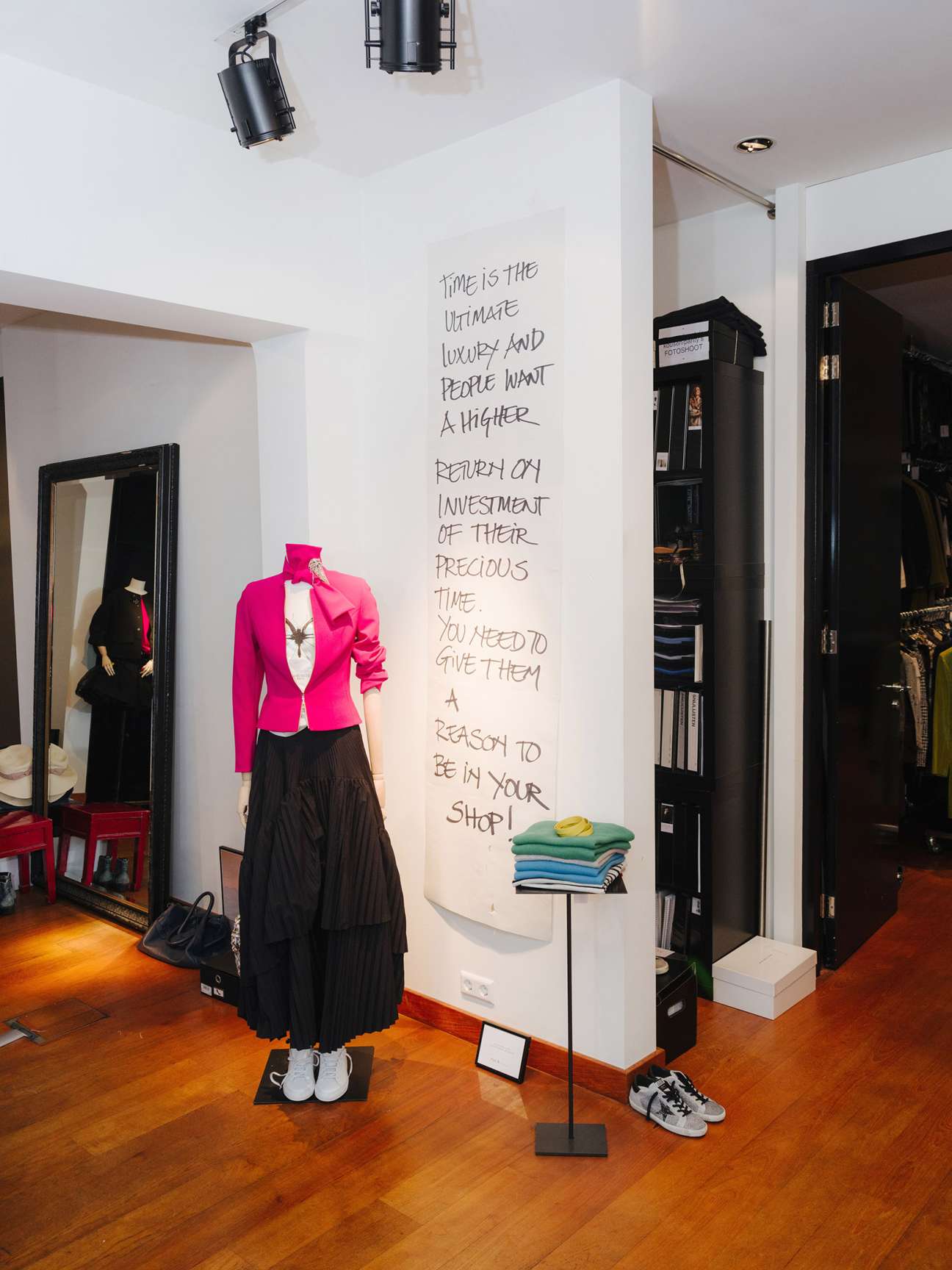 Pauw office interior with handwritten motivational motto on white wall above mannequin wearing pink blazer and black skirt.