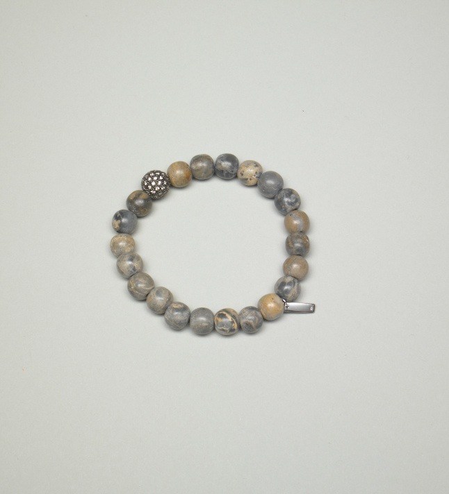 Beaded bracelet with gray and tan spheres and decorative metal accents on white background.