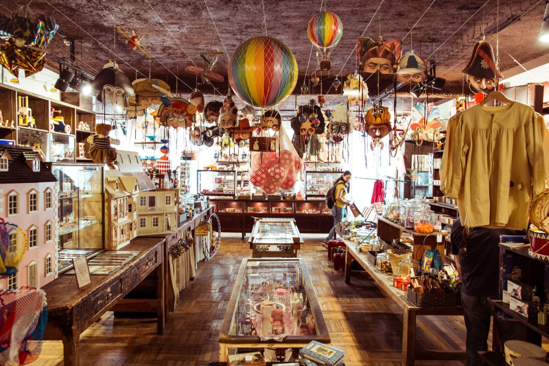 Maison Empereur's toy department with hanging decorations, dollhouses, and colorful carnival masks and balloons.