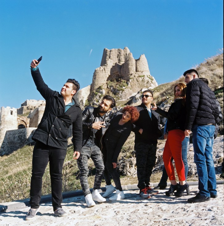 A group of Iranian visitors taking a selfie below Van's historic citadel ruins.