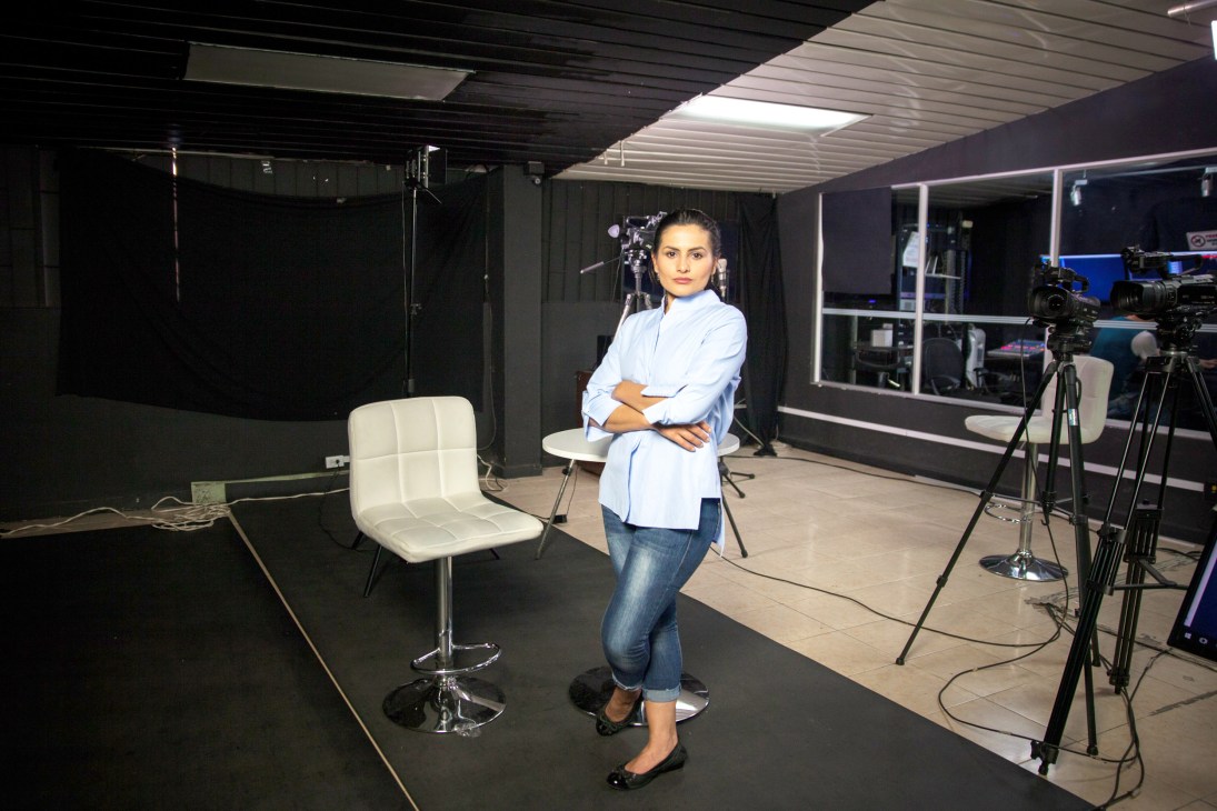 Yadira Suárez poses in the NC Noticias studio with camera equipment and white chair visible