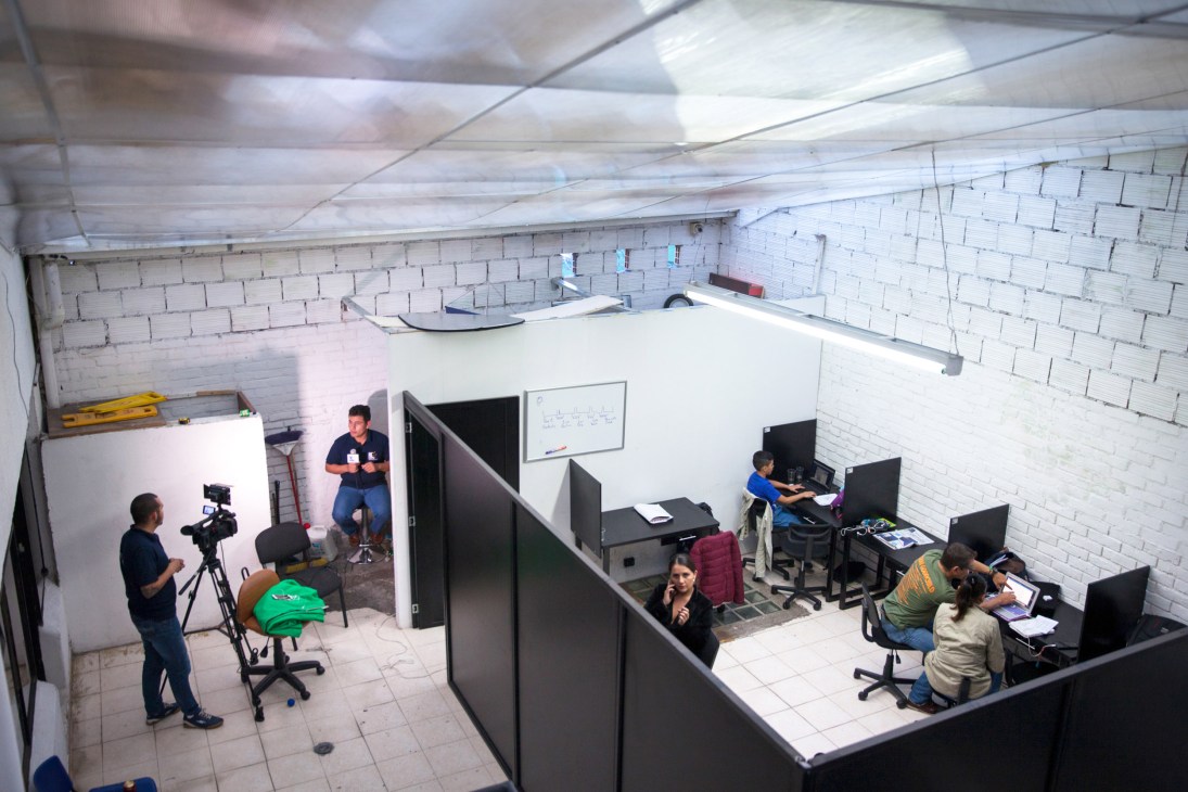 Overview of NC Noticias studio with staff working at computer stations and filming equipment.