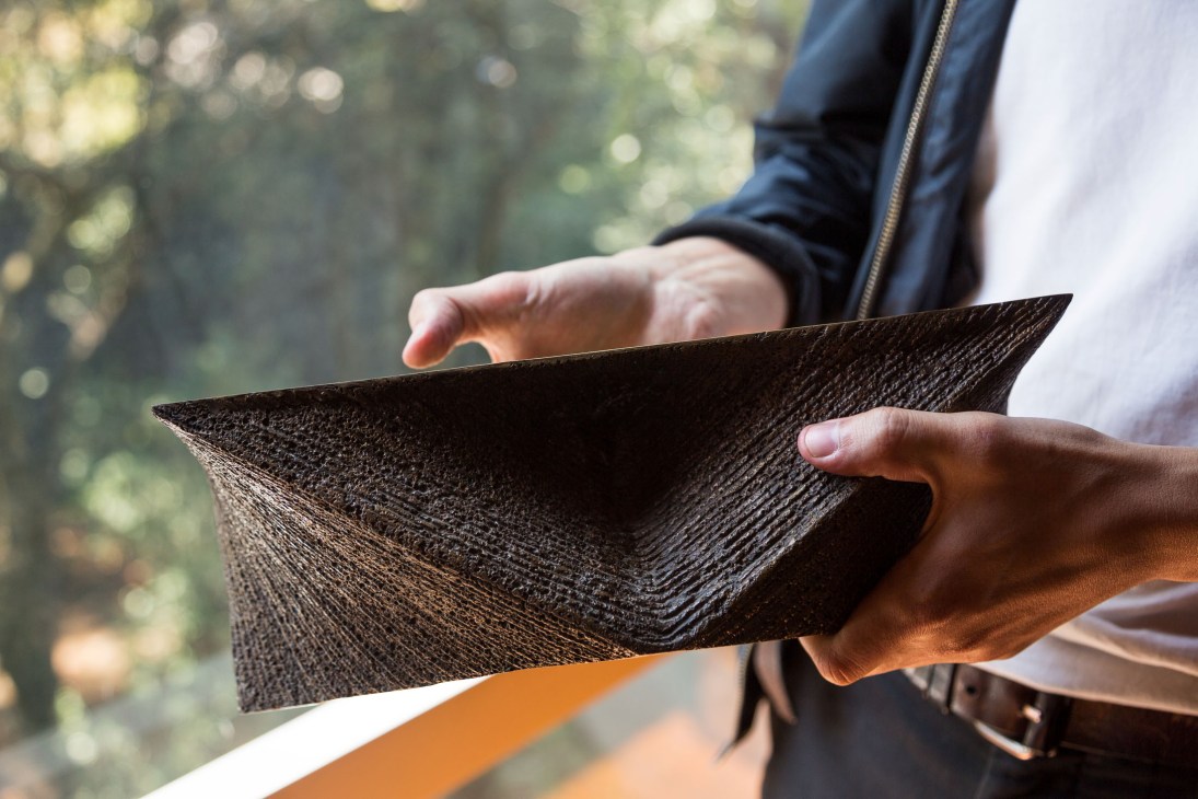 Hands holding a textured brass model of a triangular altar design by Ernesto Gallardo.
