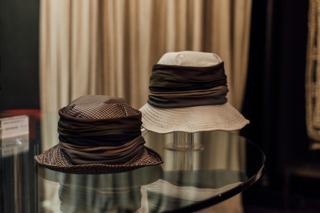 Two wide-brimmed hats with patterned crowns and dark fabric bands displayed on stands.