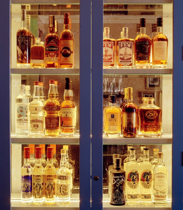 Illuminated display shelves showcasing bottles of spirits and liqueurs in The Blue Posts bar.