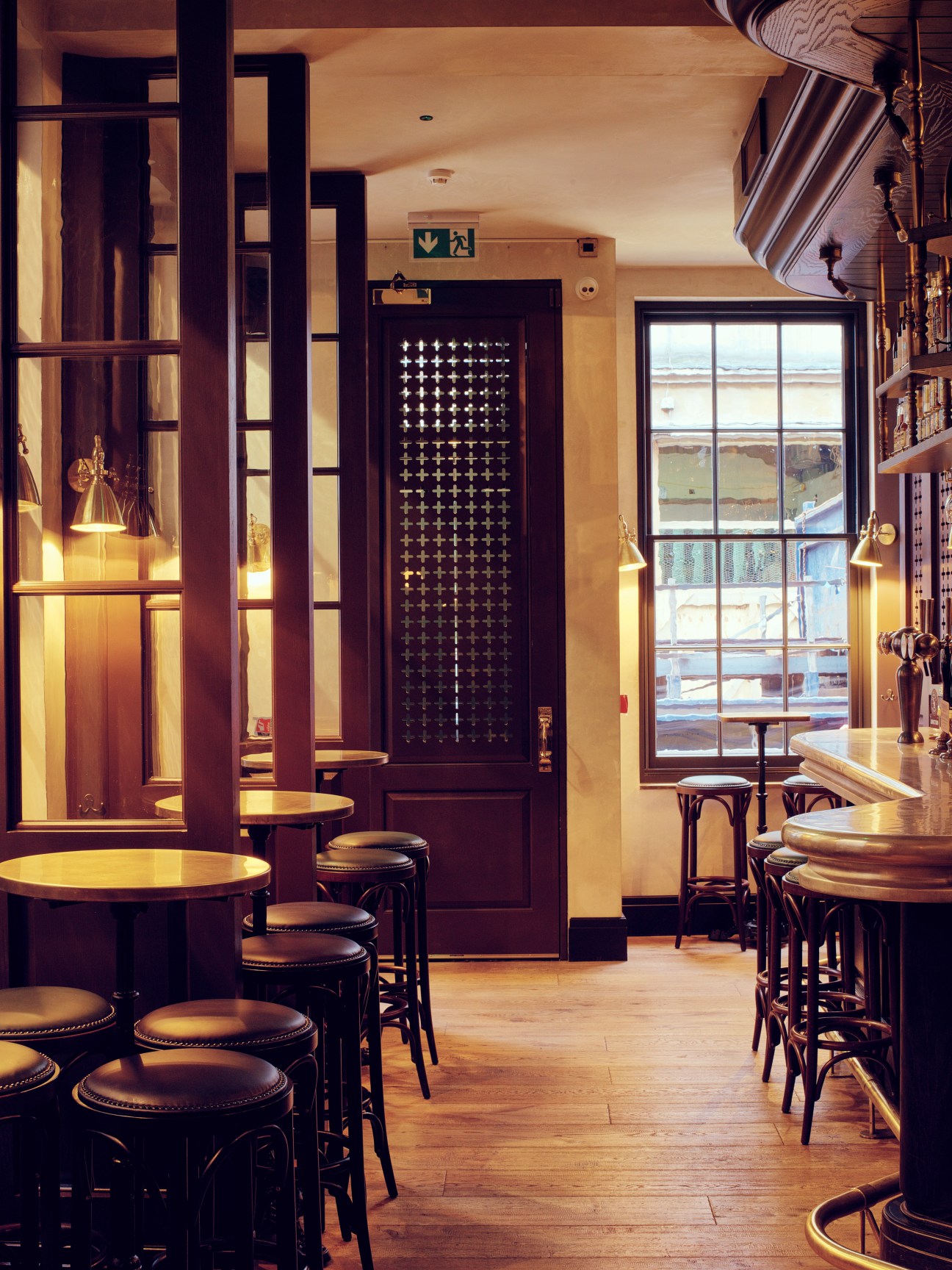The Blue Posts pub interior with wooden room dividers, round tables, bar seating, and large windows overlooking Chinatown.