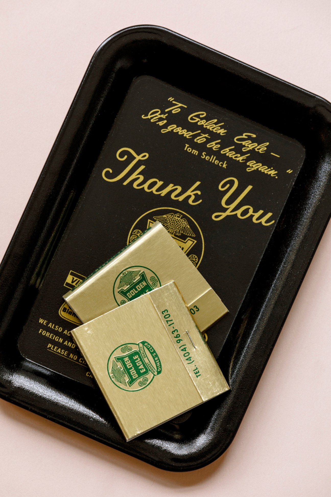 Black tray with gold 'Thank You' text and Golden Eagle branding containing gold-colored matchbooks