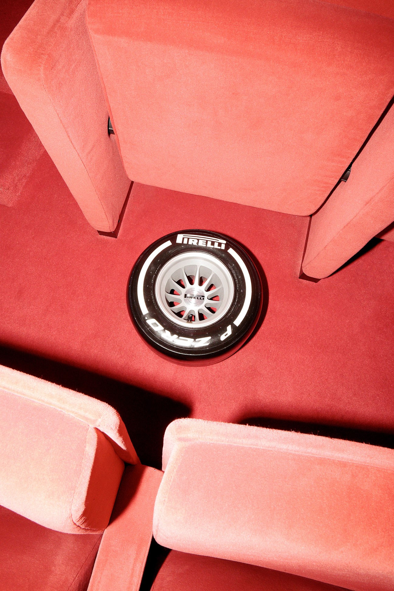 Pirelli branded tyre on red car interior with pink upholstery visible around it.
