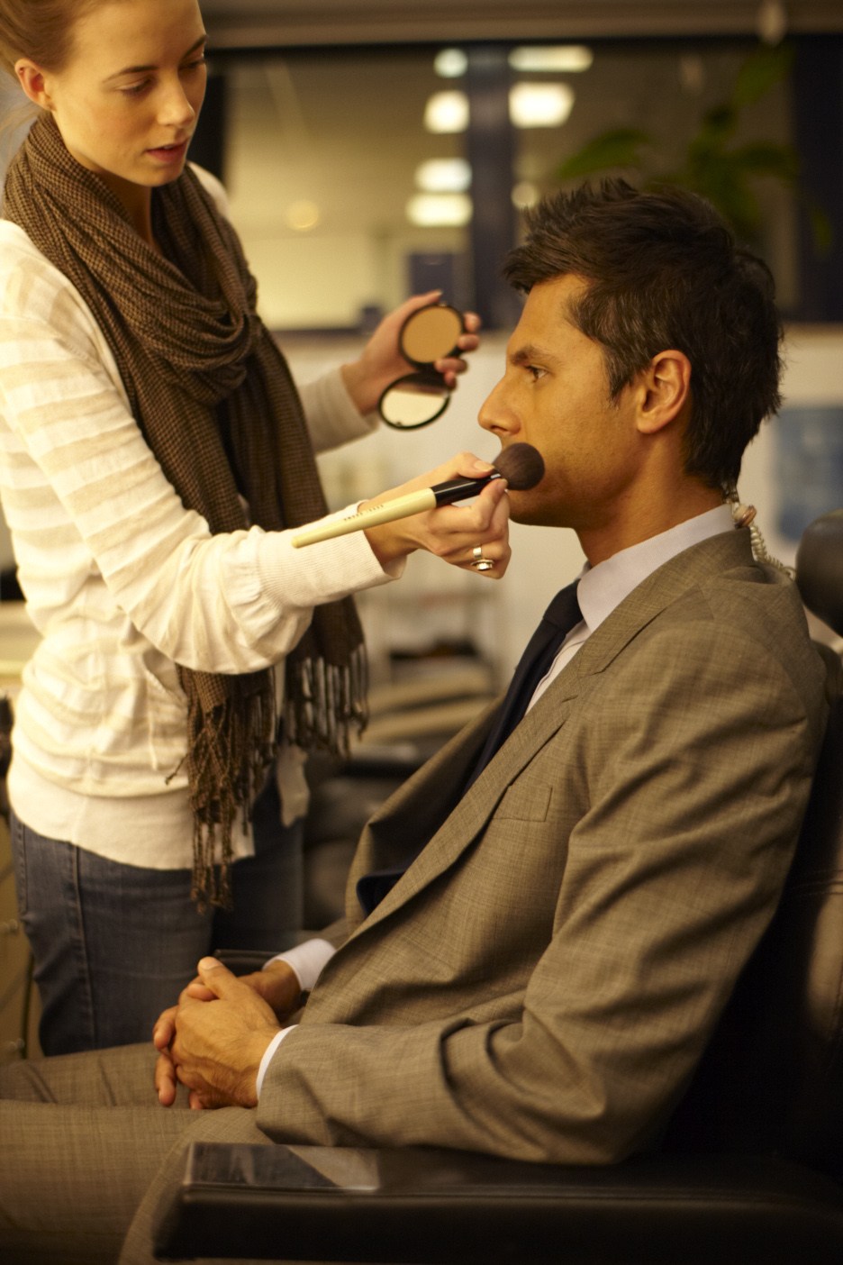A makeup artist applies powder to sports reporter Rahul Pathak's face before going on air.