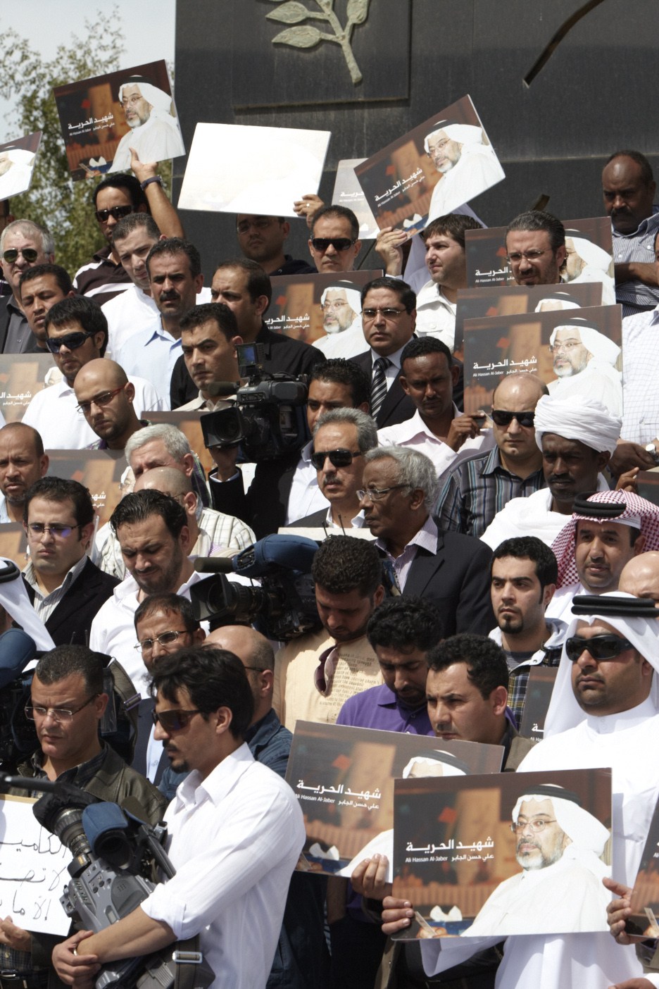 Al Jazeera staff holding memorial portraits of Ali Hassan Al Jaber at the cameraman's memorial in Doha.
