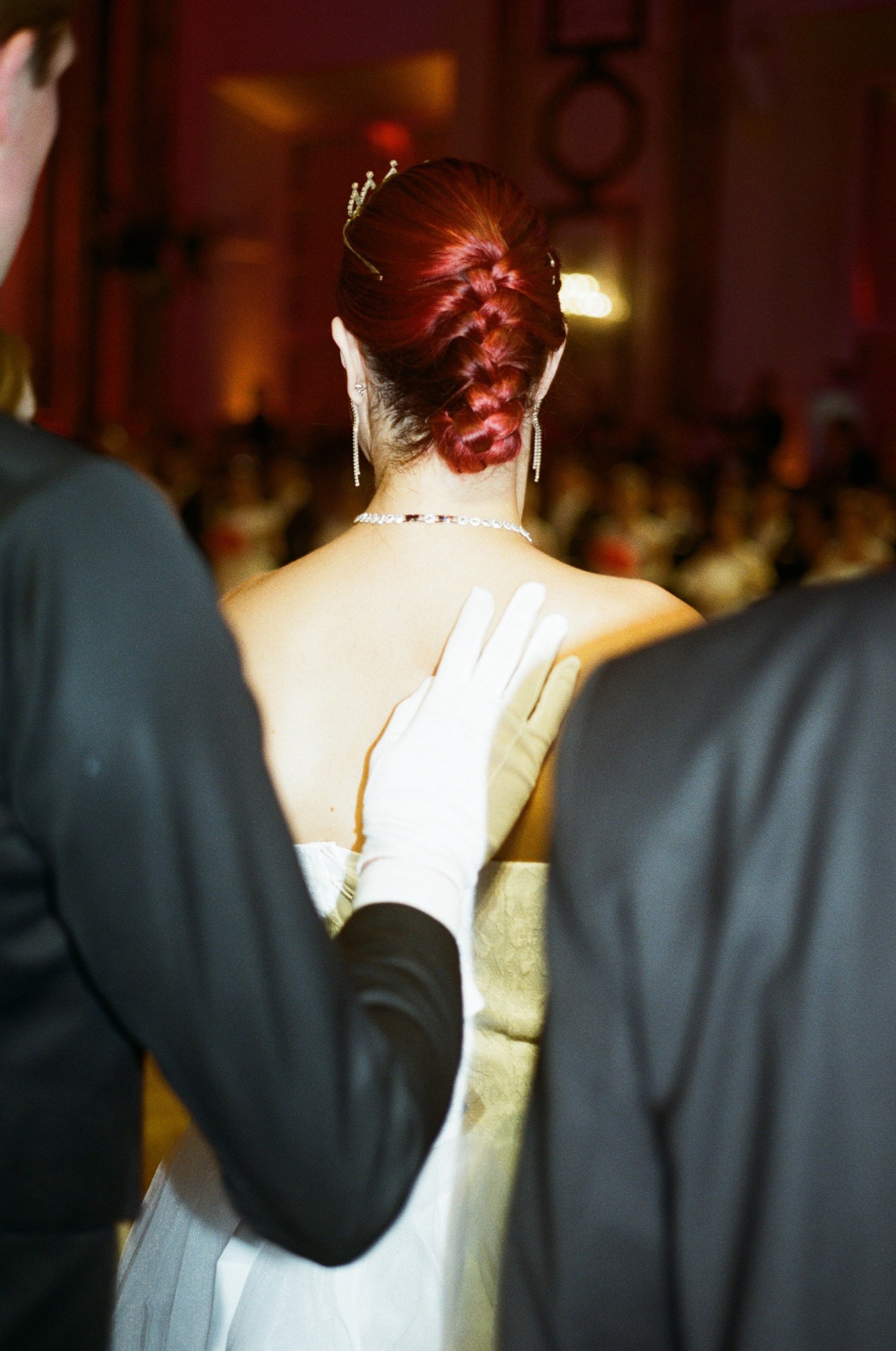 Back view of woman with elaborate braided red updo hairstyle at formal ball