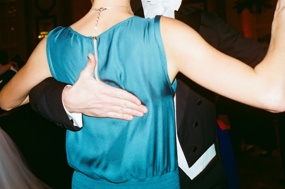 Man in formal attire places hand on woman's back while dancing at Vienna ball