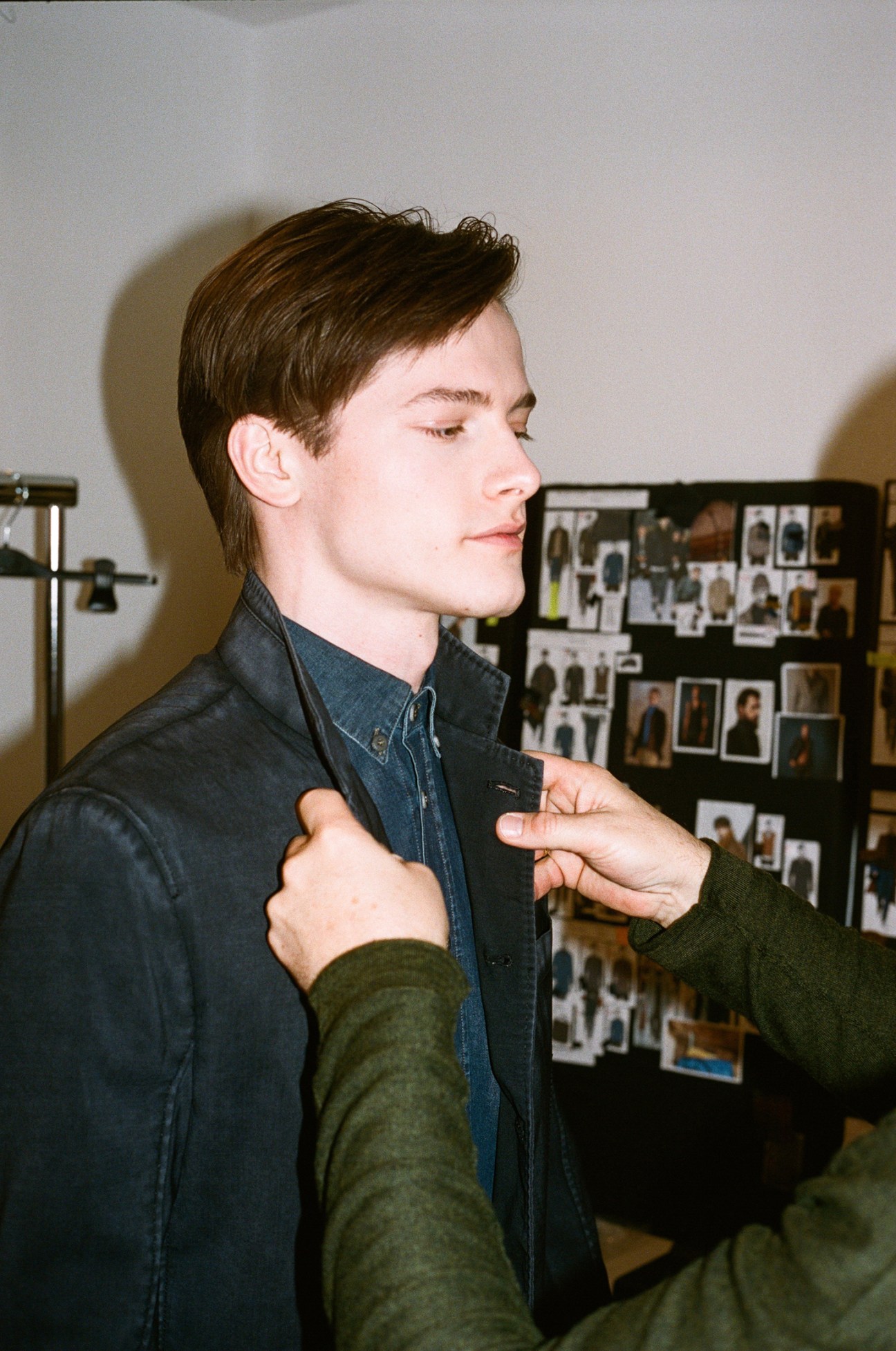 Man wearing navy Weber + Weber felted-wool blazer being fitted by hands adjusting the collar in Vienna atelier
