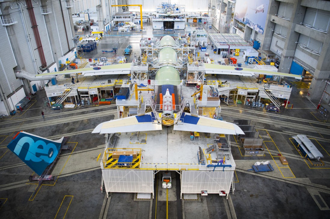 Workers fitting vertical tailplane components to Airbus A330-900 aircraft during assembly