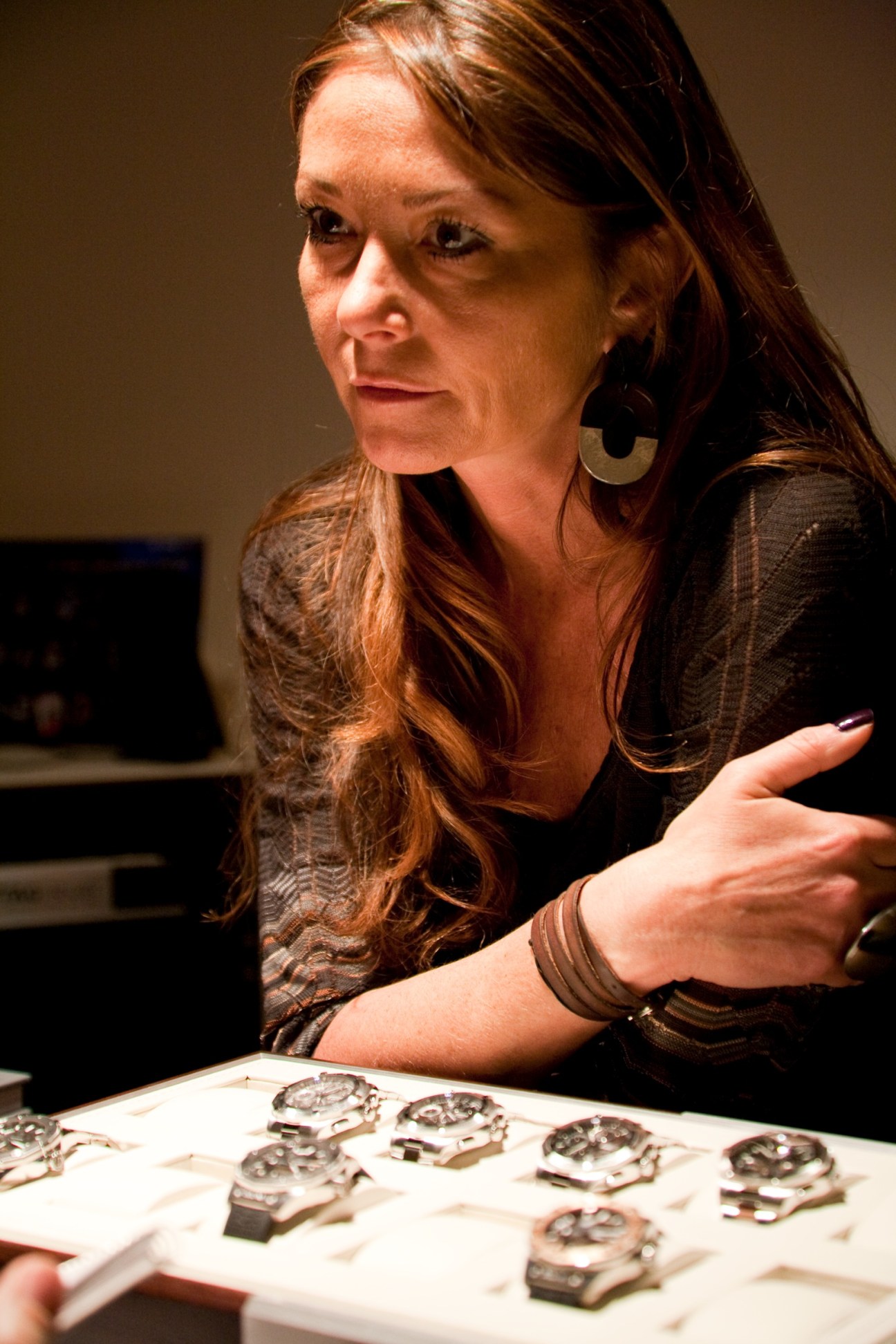 Françoise Bezzola, TAG Heuer's director of communications, gestures toward watches displayed on a table.