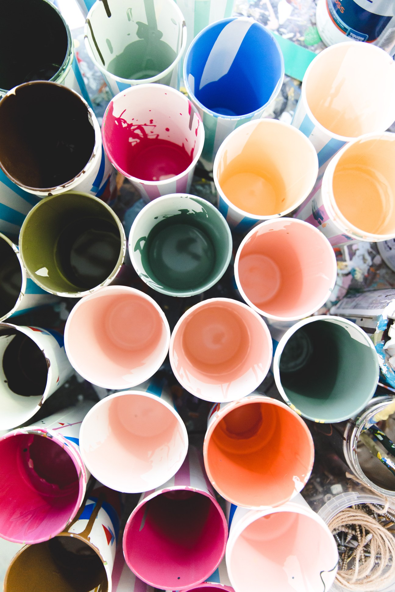 Overhead view of paint cups filled with vibrant colors including pink, blue, orange, green, and black.