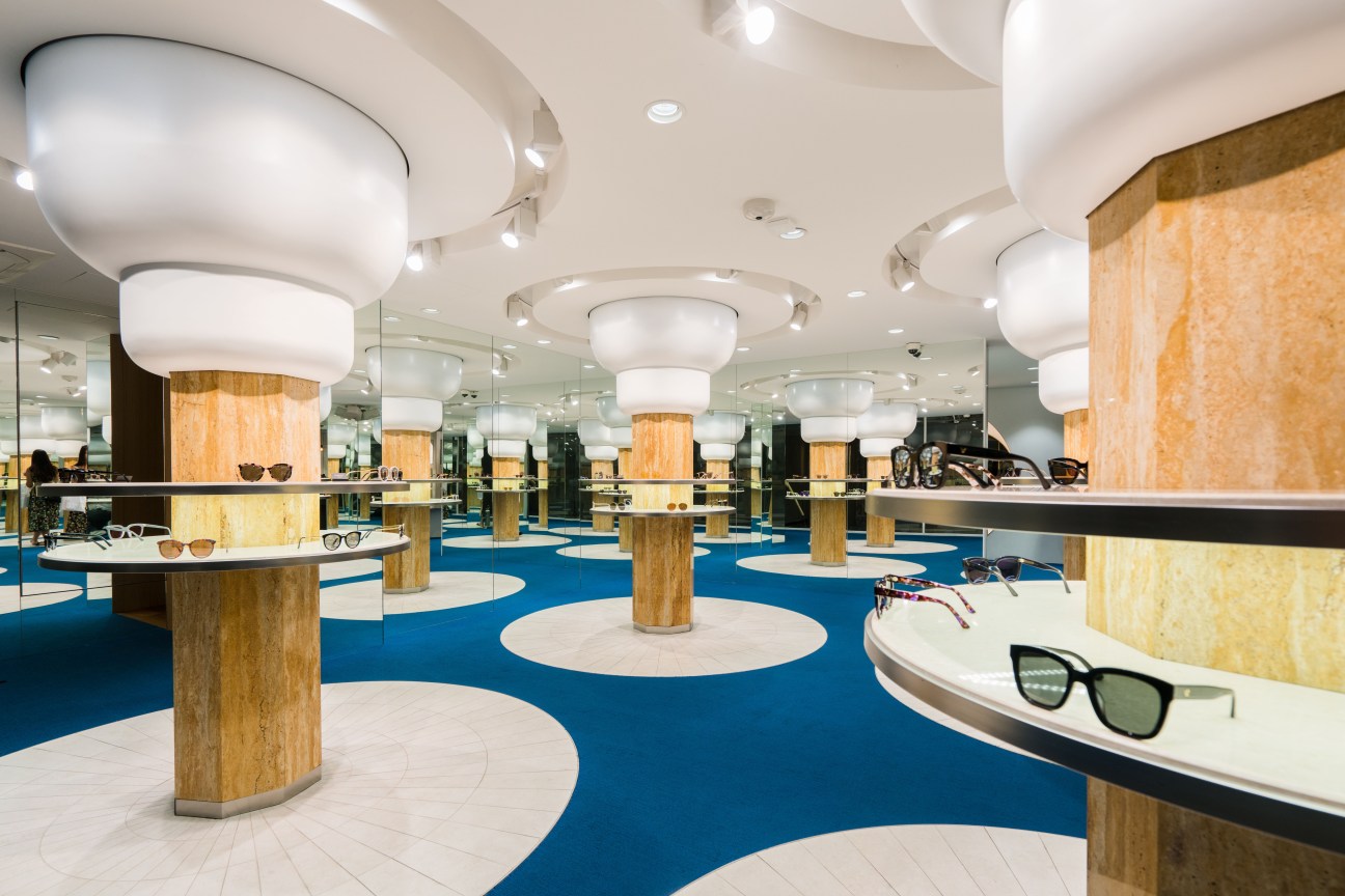 Gentle Monster's Seoul shop features wooden cylindrical display pods with white rounded tops resembling lungs, arranged on a bold blue and white geometric floor.