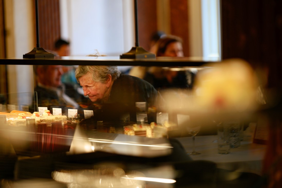 Customer examining pastries and cakes through glass display case at Gerstner cafe