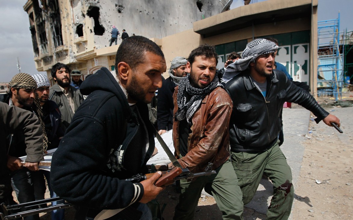 Libyan rebel fighters carrying a wounded comrade through a war-damaged street in Misurata.