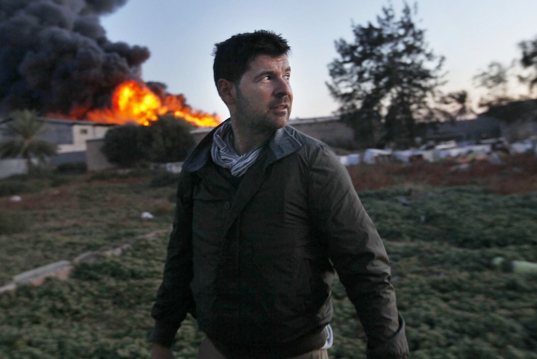 Photographer Chris Hondros in Misurata, Libya, two days before his death, with explosions visible in the background.