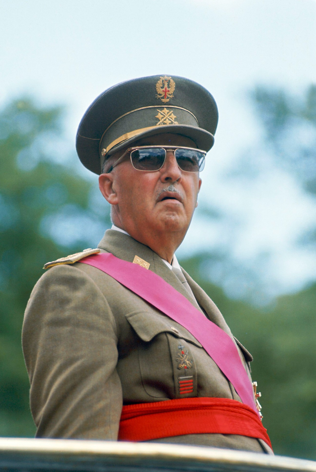 General Francisco Franco in military uniform with cap, sunglasses, and ceremonial sash.