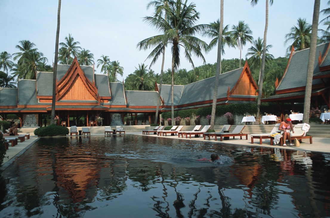 Amanpuri luxury resort in Phuket with traditional Thai architecture, palm trees, and poolside loungers.