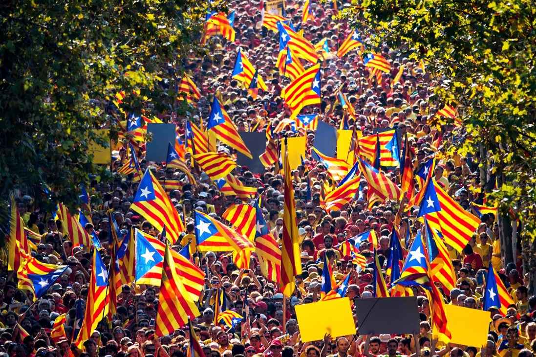 Crowd of pro-independence demonstrators waving blue, red and yellow Catalan flags at a National Day of Catalonia rally in Barcelona.