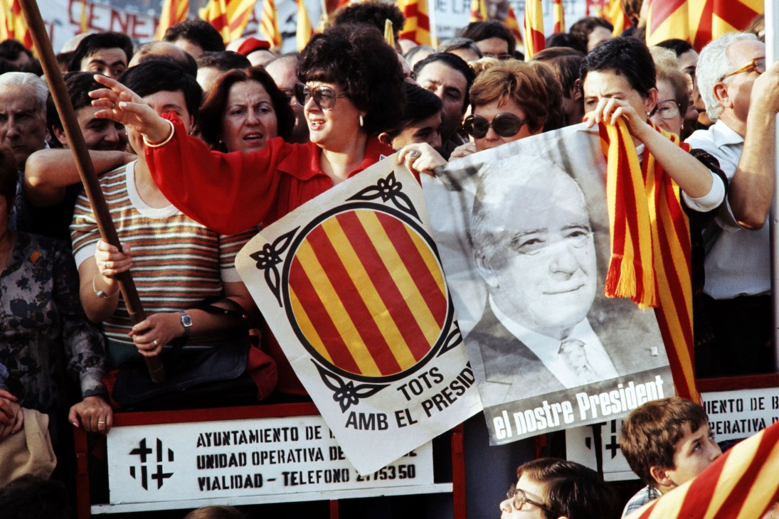 Spanish women holding Catalan independence flags and a portrait at a pro-independence rally celebrating Josep Tarradellas's return to Barcelona.