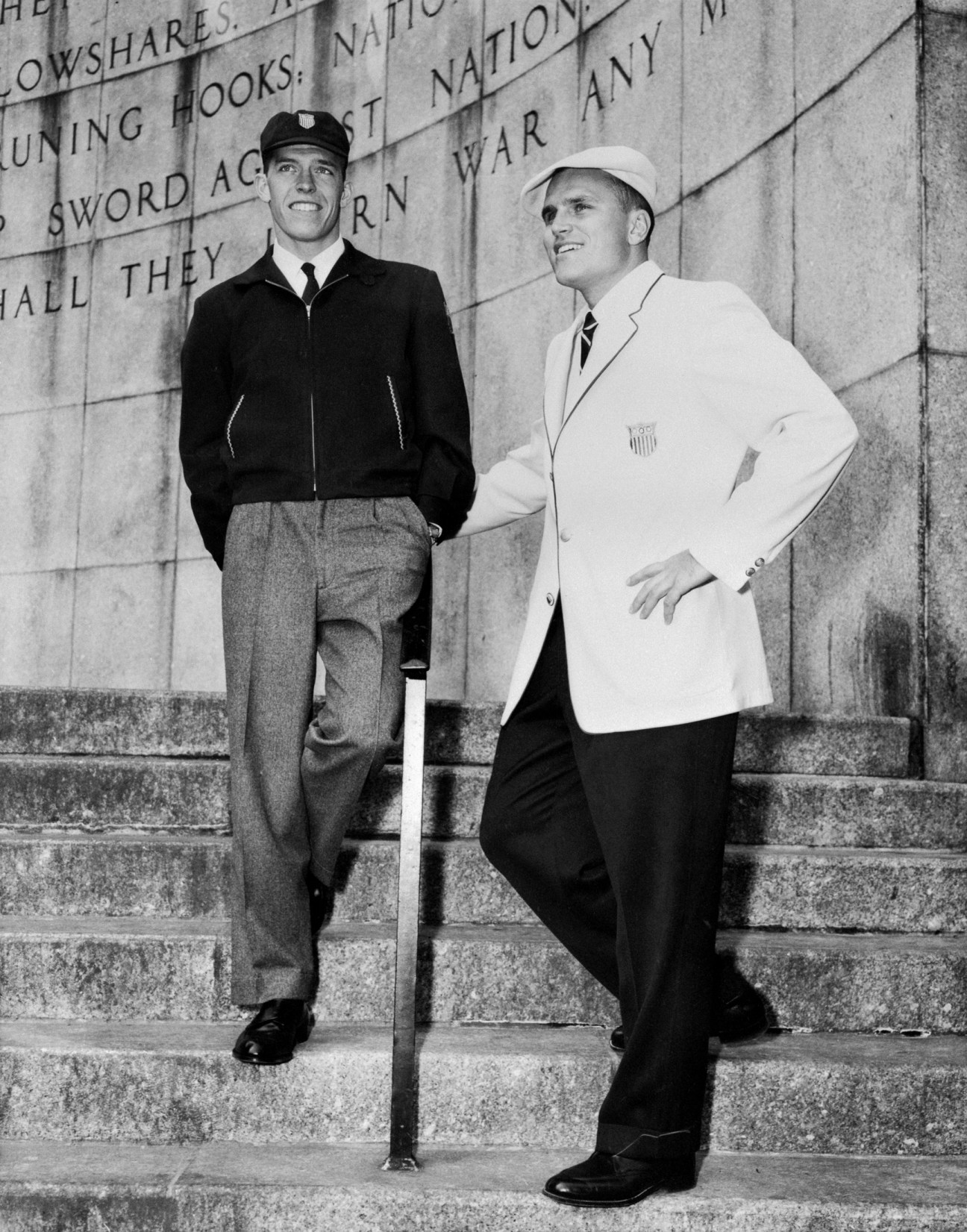Two men in 1956 US Olympic uniforms: one wearing a black jacket with grey trousers, the other in a white blazer with black trousers.