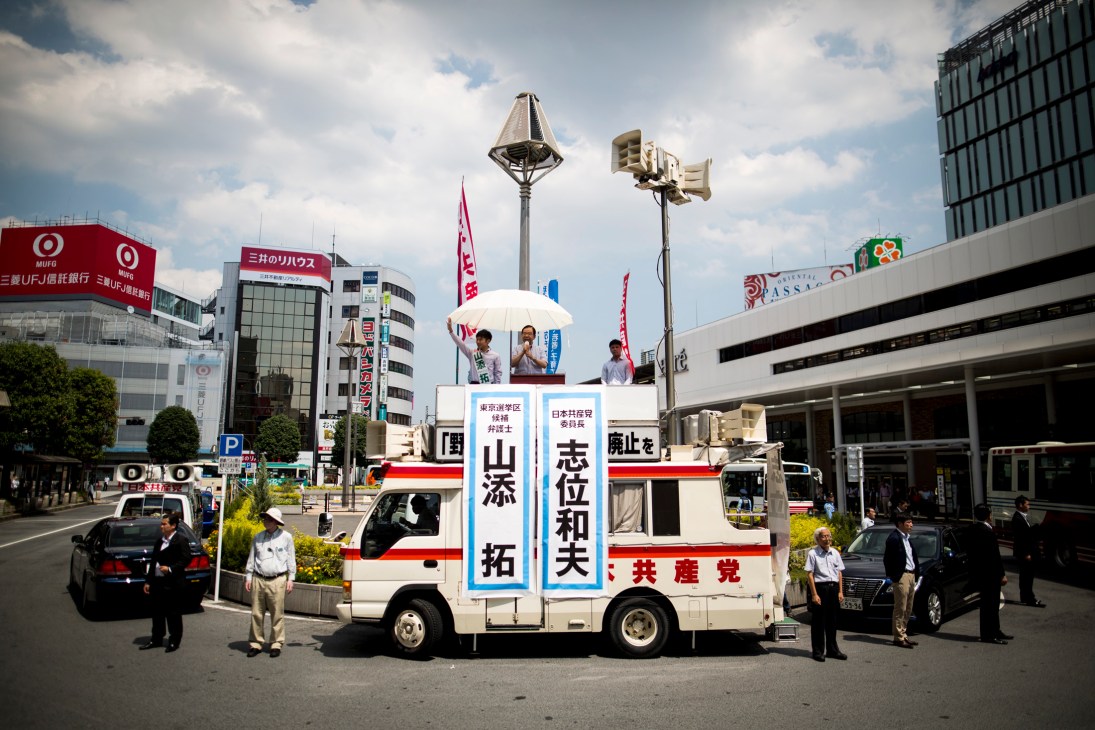 Japanese Communist Party campaign truck with loudspeakers and candidate names parked on busy urban street