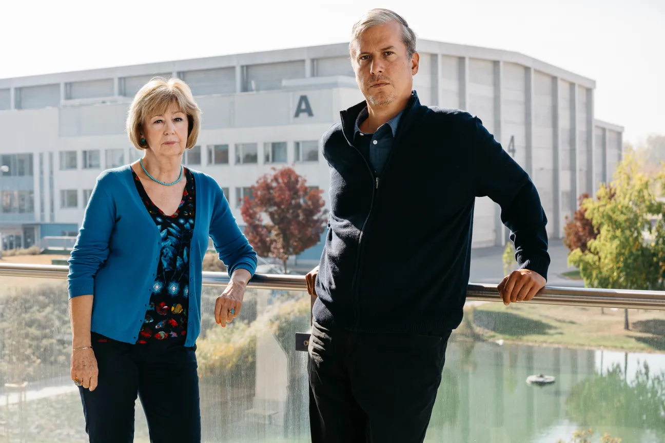 Origo CEO Marta Fekszi Horvath and head of production Mihaly Korom stand by a window overlooking a modern studio building.