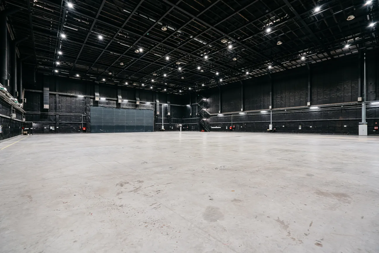 Empty soundstage at Origo Studios with concrete floor and industrial lighting rig overhead.