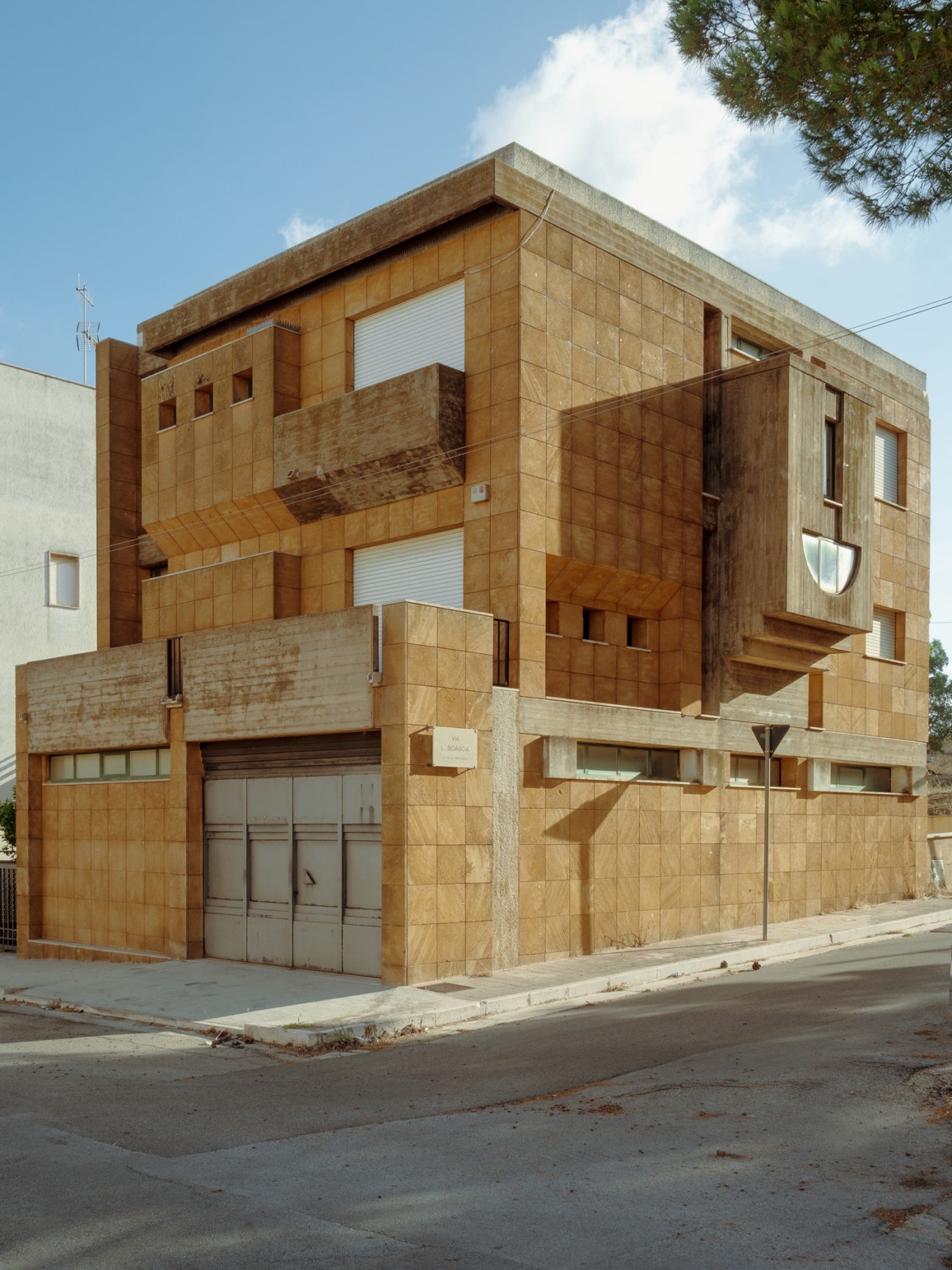Modern apartment building with tan stone facade and geometric window arrangement near Gibellina Nuova