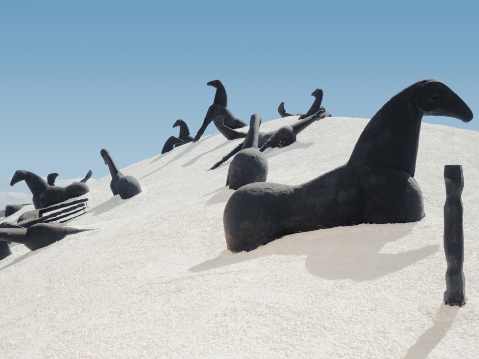 Black sculptural forms of horses and riders emerging from white sand in Mimmo Paladino's 'Montagna di Sale'.