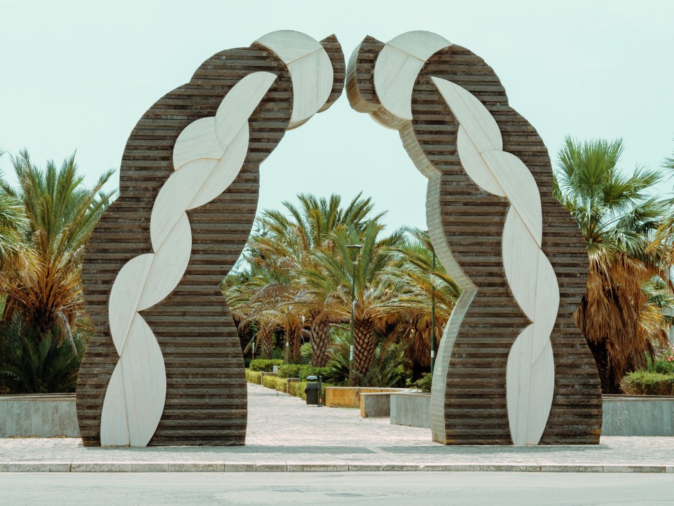 Modern sculptural gate entrance with wooden and white curved forms by Pietro Consagra