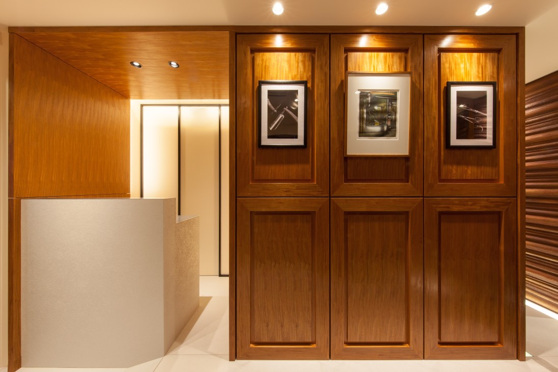 Modern salon interior with wooden wall paneling, recessed lighting, and a white reception desk.