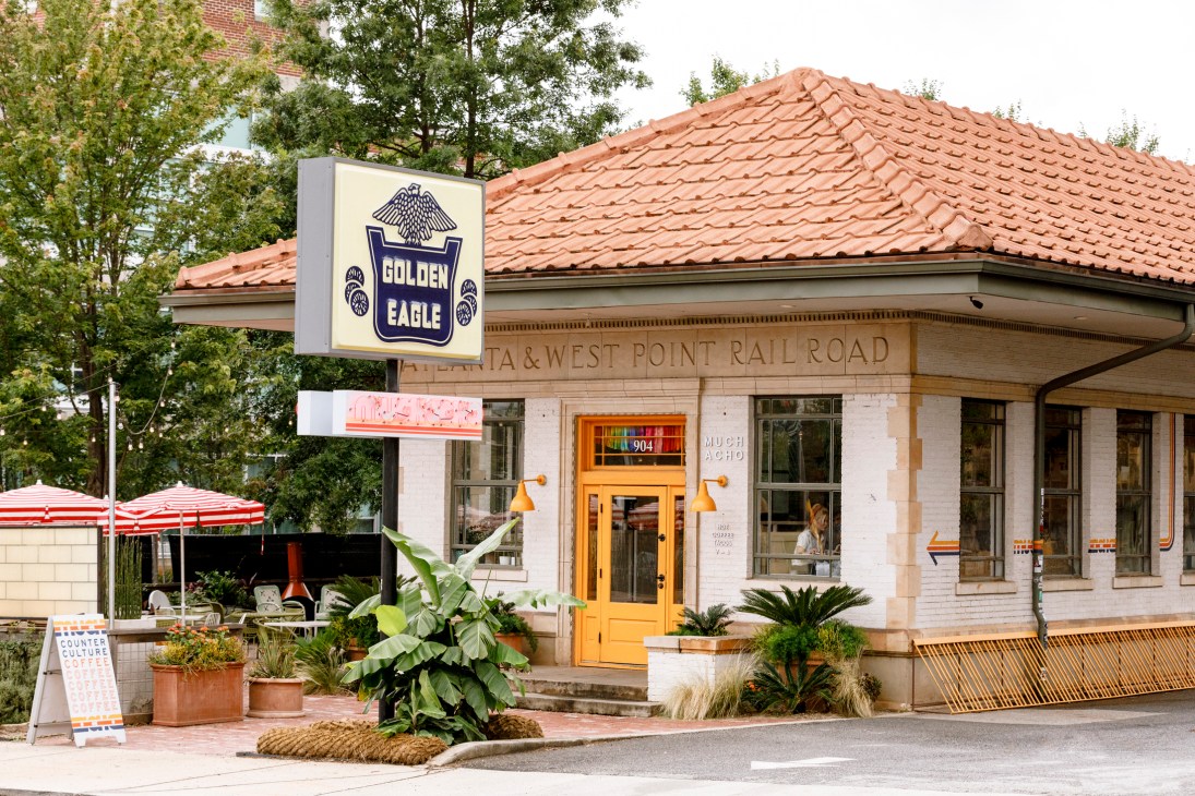 White brick building with clay tile roof featuring Golden Eagle and Atlanta & West Point Rail Road signage